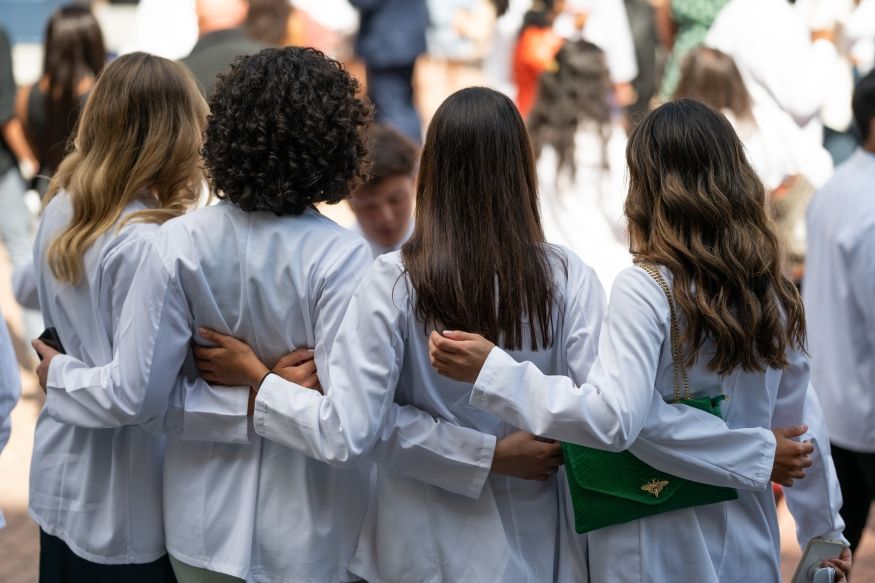 the backs of four students wearing white coats
