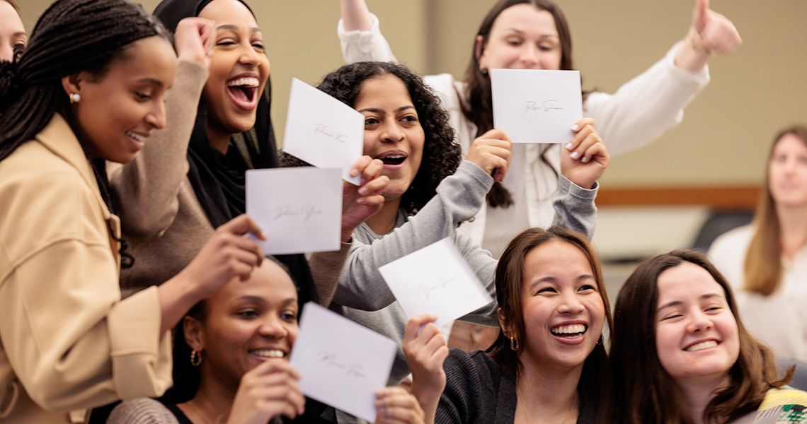 Students in group holding up match envelopes