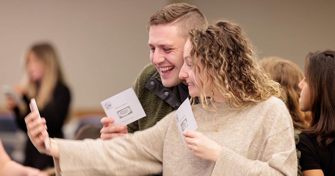 Students taking photos with match envelopes