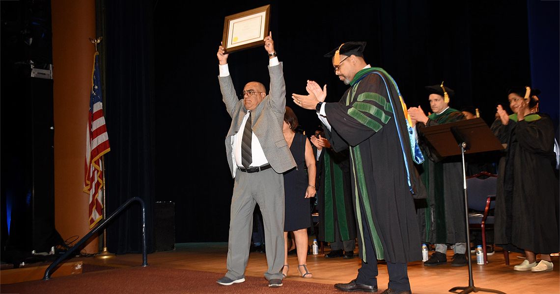 Parent holds certificate in remembrance of his son who passed.