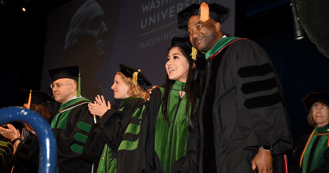 Platform party stands and claps at graduation ceremony