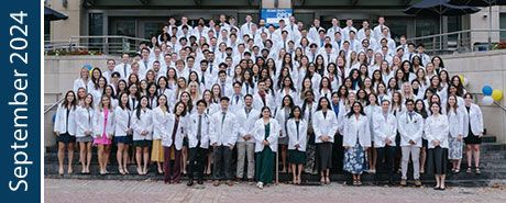 MD Class of 2028 in White Coats on steps of Gelman Library