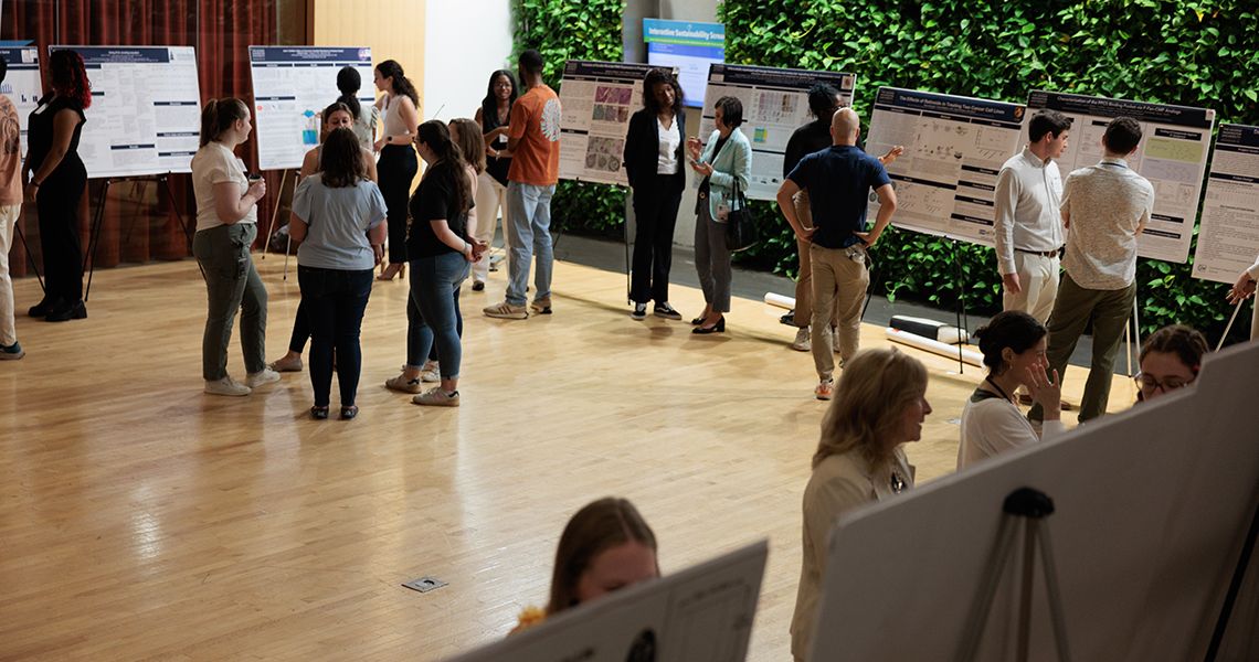 Students at their research posters discussing their work