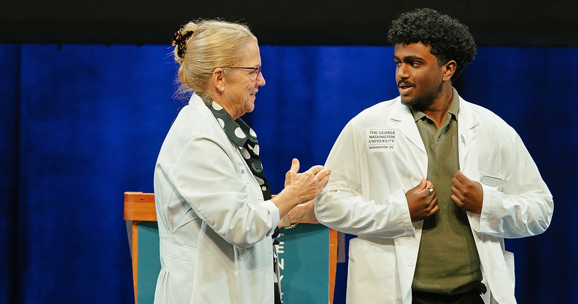 Dean Bas congratulates MD student in white coat