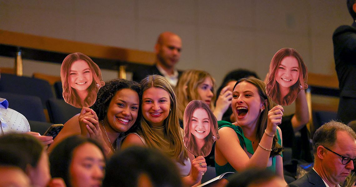 Friends pose with cutouts of their friend’s face