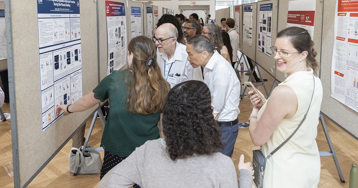 Faculty members review research posters in exhibit hall
