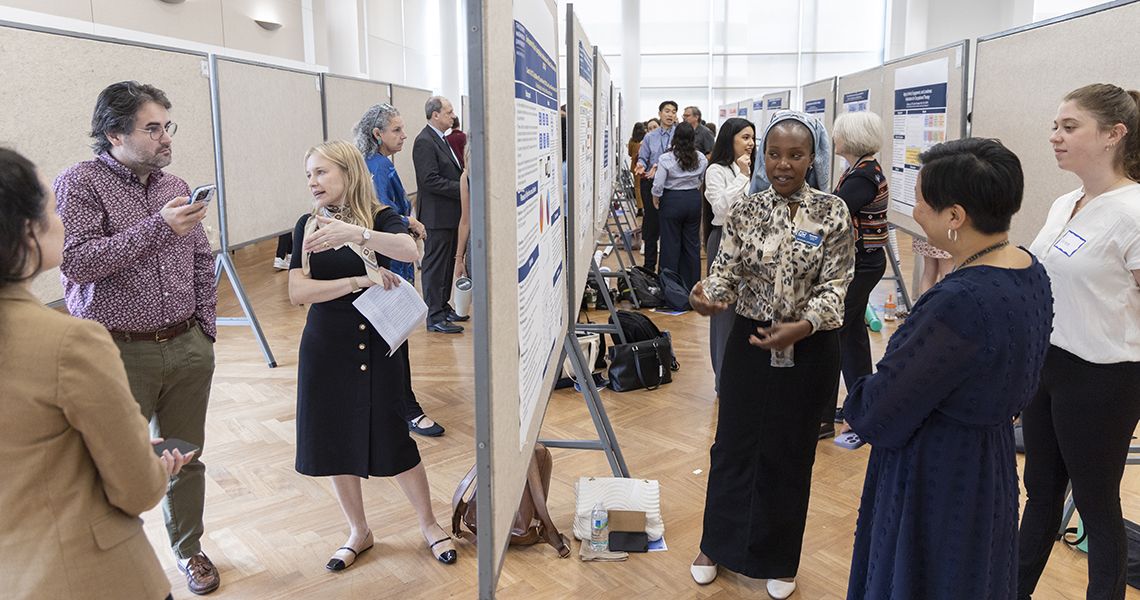 Presenters and guests discuss research posters in exhibit hall