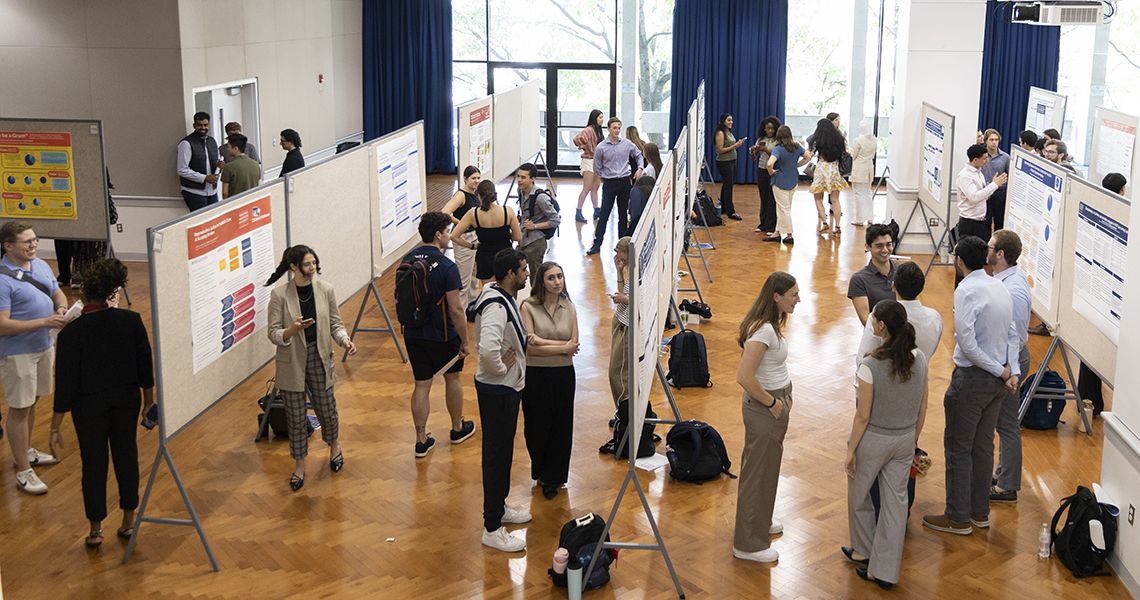 Presenters and guests discuss research posters in exhibit hall