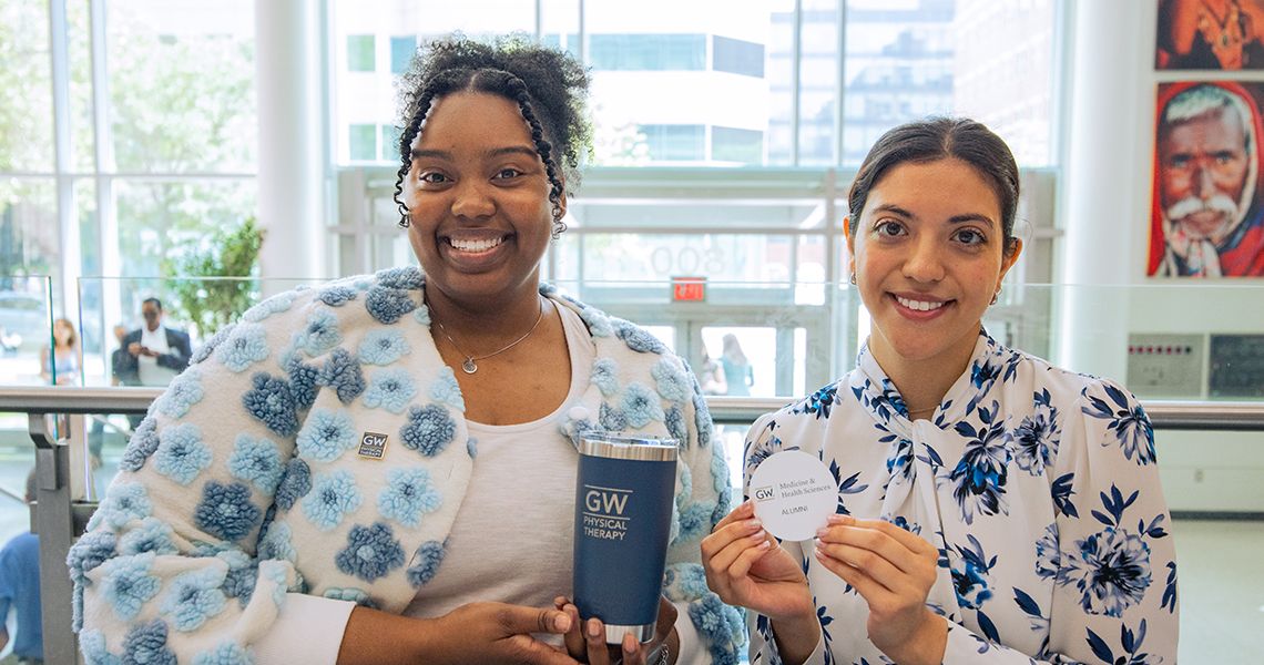 PT students holding alumni coffee mugs and other swag
