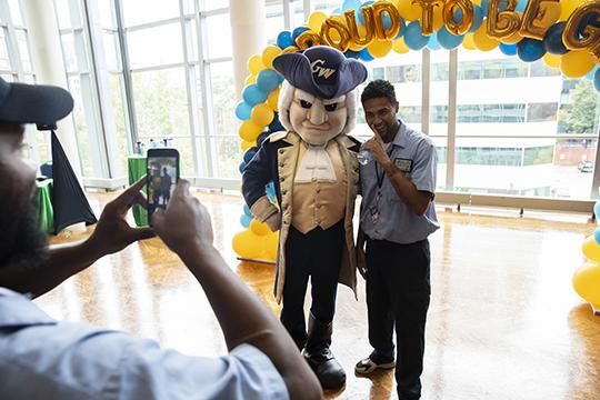 GW staff posing for a picture with George the GW Mascot