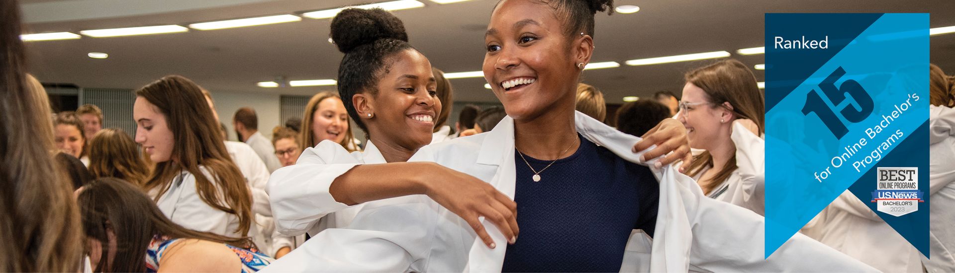 a student putting a white coat on another student | banner that reads Ranked 15 for online bachelor's programs, with the USNWR badge