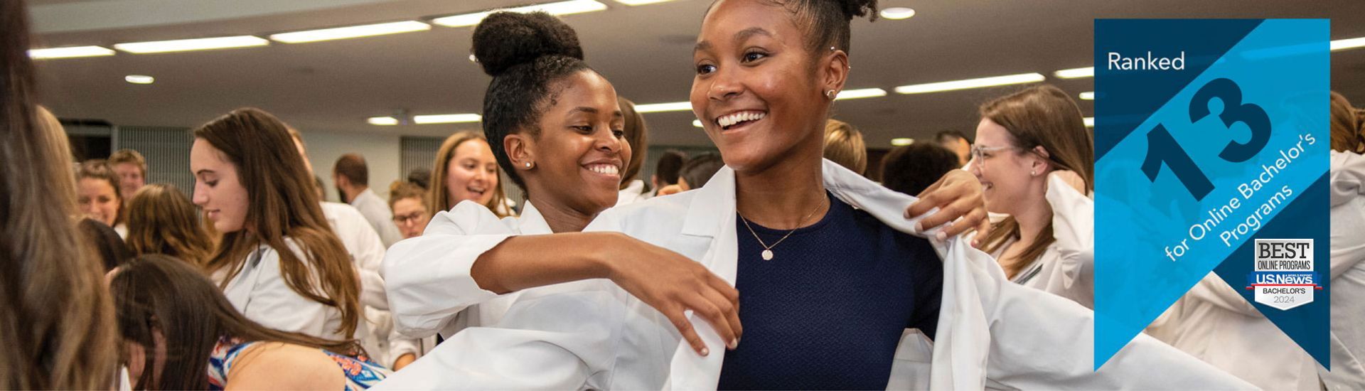 A student putting a white coat on another student | banner that reads Ranked 15 for online bachelor's programs, with the USNWR badge
