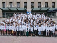 Class of 2028 poses in white coats on steps of Gelman Library