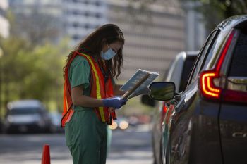 Health care worker collecting a covid-19 test sample from a patient in a car