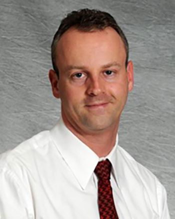 Michael Irwig posed for a portrait in a white shirt and red tie