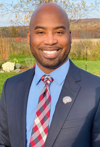 Nathan Smith smiling for a portrait in front of a field