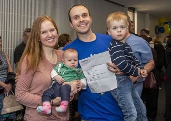 A GW medical student posing his wife and two children and holding a white envelope