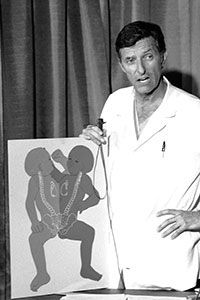 Dr. Judson Randolph standing with a diagram of conjoined twins