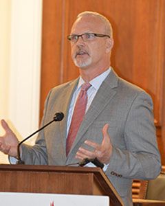 Dr. Ken Harwood speaking from a podium