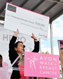Mandi Pratt-Chapman, holding a $100,000 check and standing at a podium