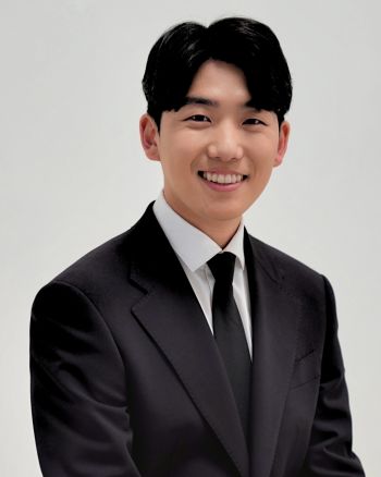 Image of an asain man with short dark hair wearing a black suit and white collared shirt