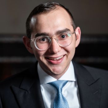 Image of white man wearing glasses, a white collared shirt, and blue tie