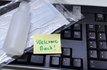 A sample bottle, a mask and a note that says 'Welcome Back!' lie on a keyboard