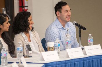 Three panelists sitting at a table and smiling