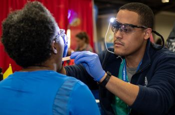 A GW medical professional examines a person's mouth during the Health & Fitness expo