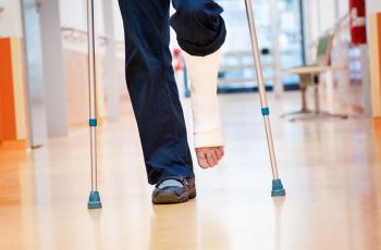 A patient walking with crutches and a cast around their left leg