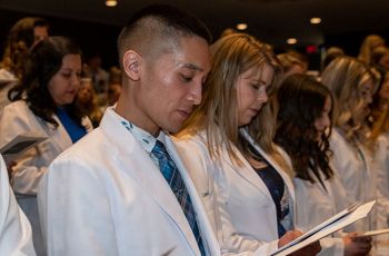 PA students wearing white coats and reciting an oath