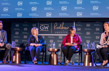 Four panelists sit together in front of a 'GW Rodham Institute' labeled wall
