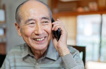 Elderly man smiling and talking on an iPhone