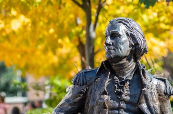 Statue of George Washington in front of a yellow leaved tree
