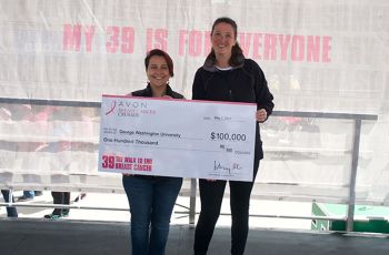 Mandi Pratt-Chapman and a woman standing with a large check from the Avon Foundation