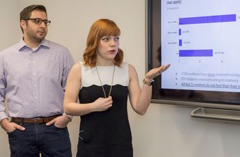Two GW medical students presenting next to a screen with a bar graph