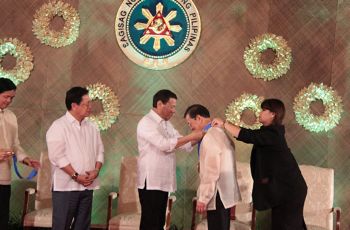 Philippines President Rodrigo Duterte placing a medal on Dr. Pedro A. Jose in a ceremonial room