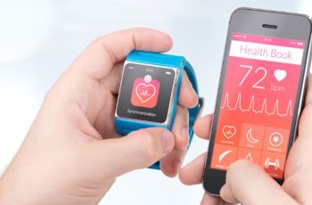 A person holding a smartphone and a smart watch displaying heart health data