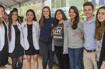 Several GW medical students standing together beneath an event tent