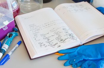 An open laboratory journal among medical gloves and other medical equipement