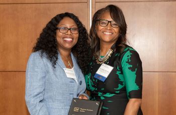 Drs. Mary A. Ogunsanya and Karen Wright standing with each other and holding an award