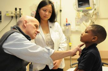 Dr. Stephen Teach and a nurse examining a child patient's neck 