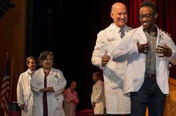MD student receives his short white coat from SMHS Dean Jeffrey Akman
