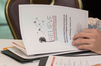 Person opening a packet titled 'Believe' at a table