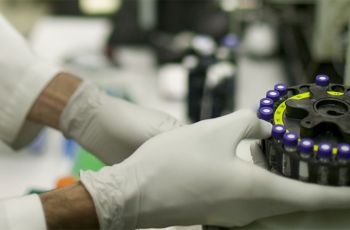 A lab worker handling a vial centrifuge