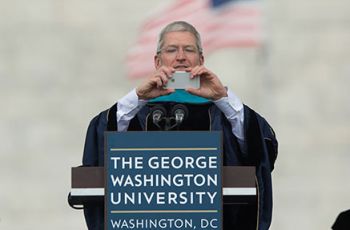 Tim Cook standing at a podium adn holding an iPhone
