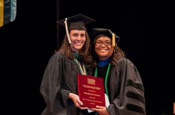Dr. Karen Wright standing with Elizabeth Prevou in graduation regalia