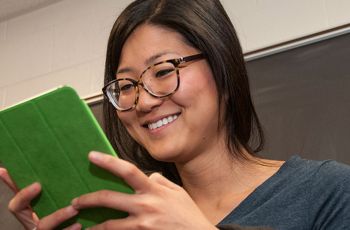 A person smiling at an iPad with a green case