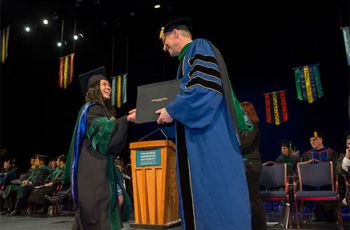 Dean Akman shakes hands with a graduating M.D. student