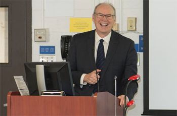 Dr. Joseph C. Kolars smiling from a podium